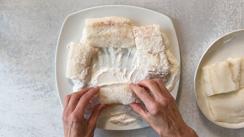 Dredging cod filets in rice flour on plate