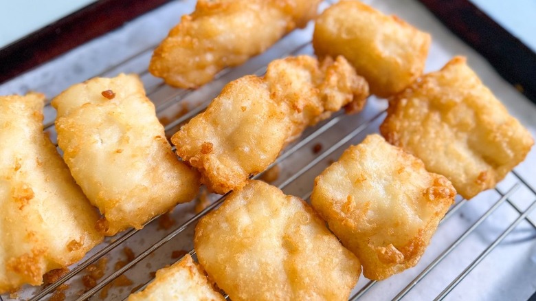 Golden brown battered cod filets on rack