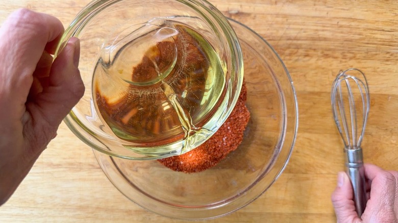 Pouring hot fryer oil into spices for Nashville hot glaze