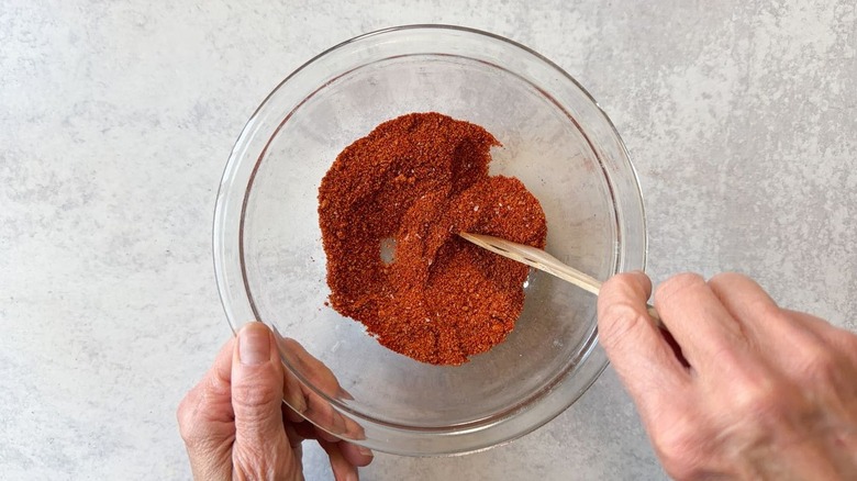 Mixing together spices and brown sugar with a wooden spoon in a small glass bowl