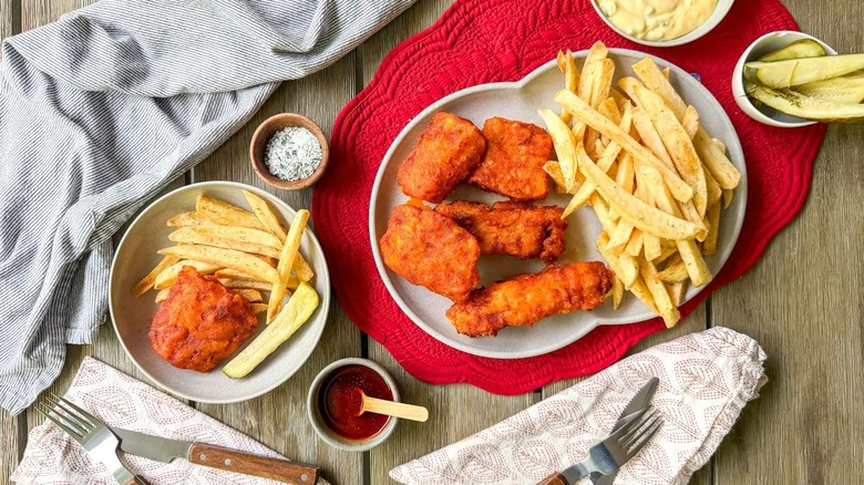 Nashville hot fish and chips on serving platter and plate with pickles and condiments