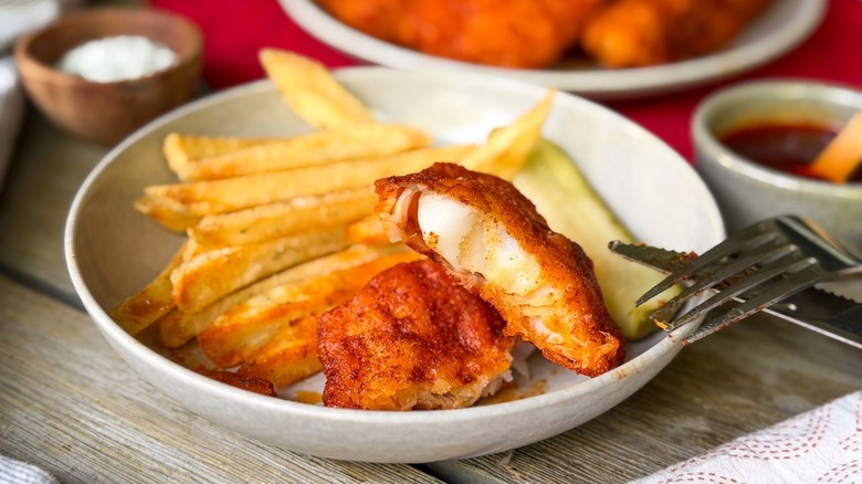 Nashville hot fish and chips with piece of fish on fork close up