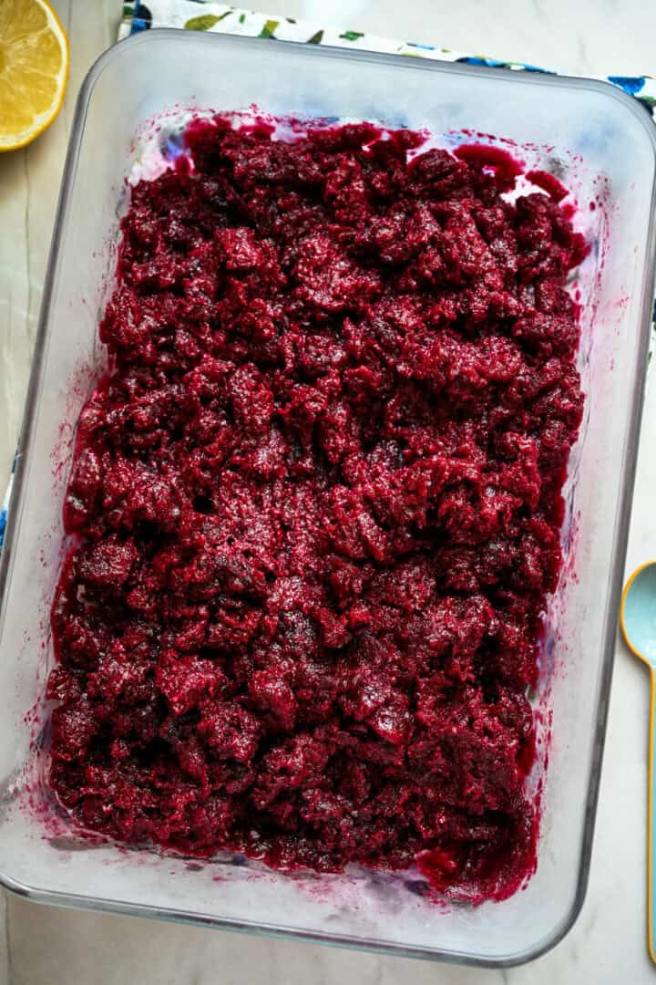 Blueberry granita mixture in glass container before freezing.
