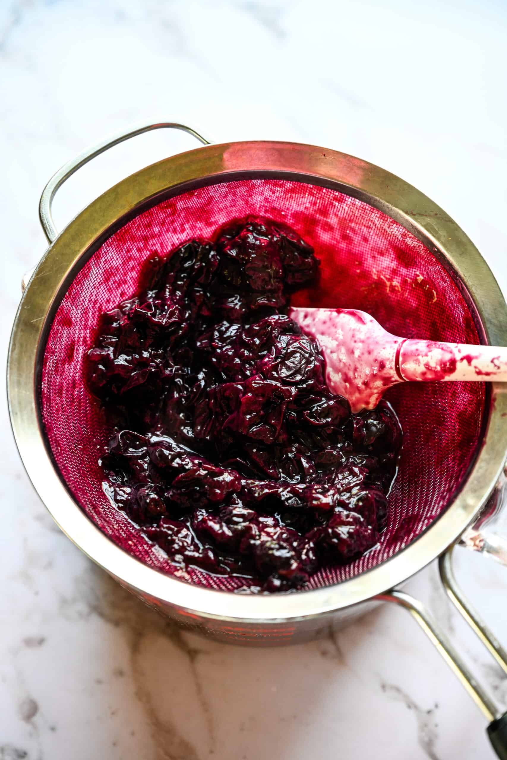Straining blueberry mixture to separate the juice and skins.
