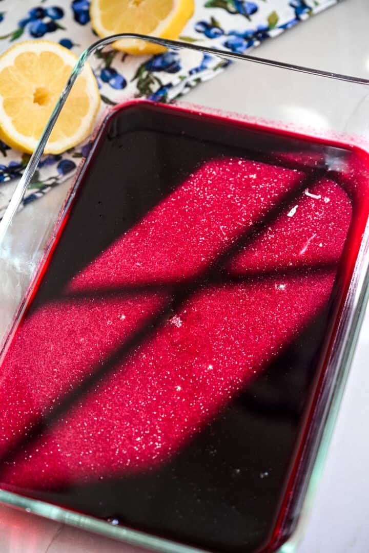 Blueberry granita mixture in glass container before freezing.
