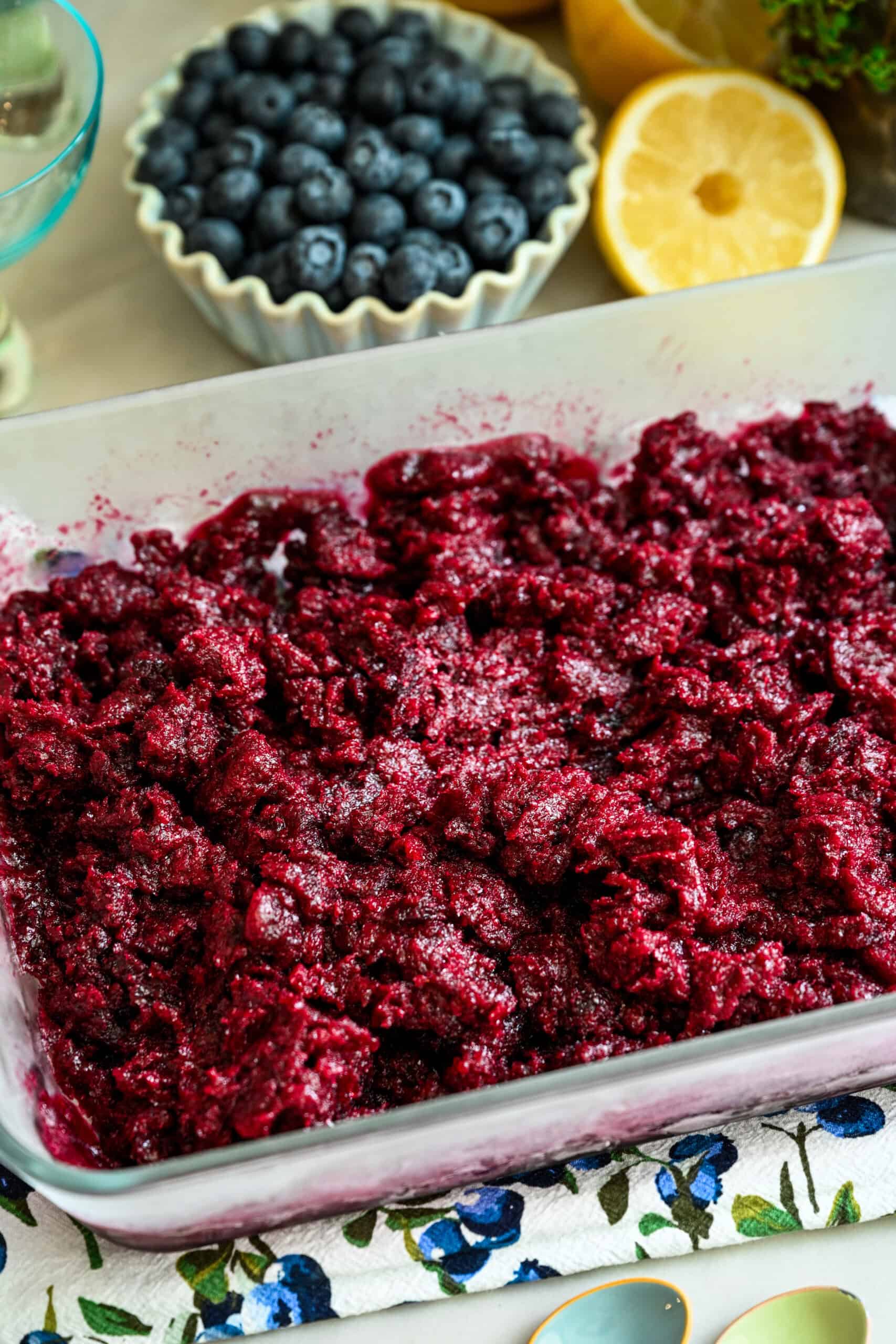 Blueberry granita mixture in glass container before freezing.