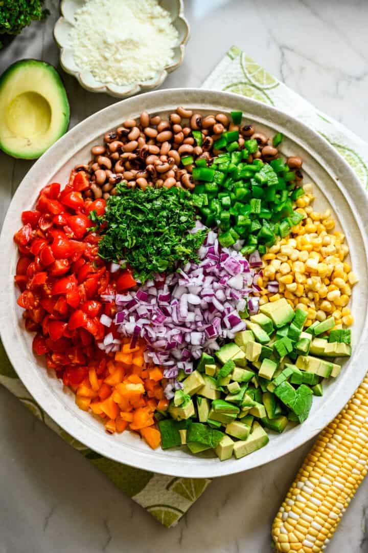cowboy caviar salad ingredients in a bowl before mixing together.