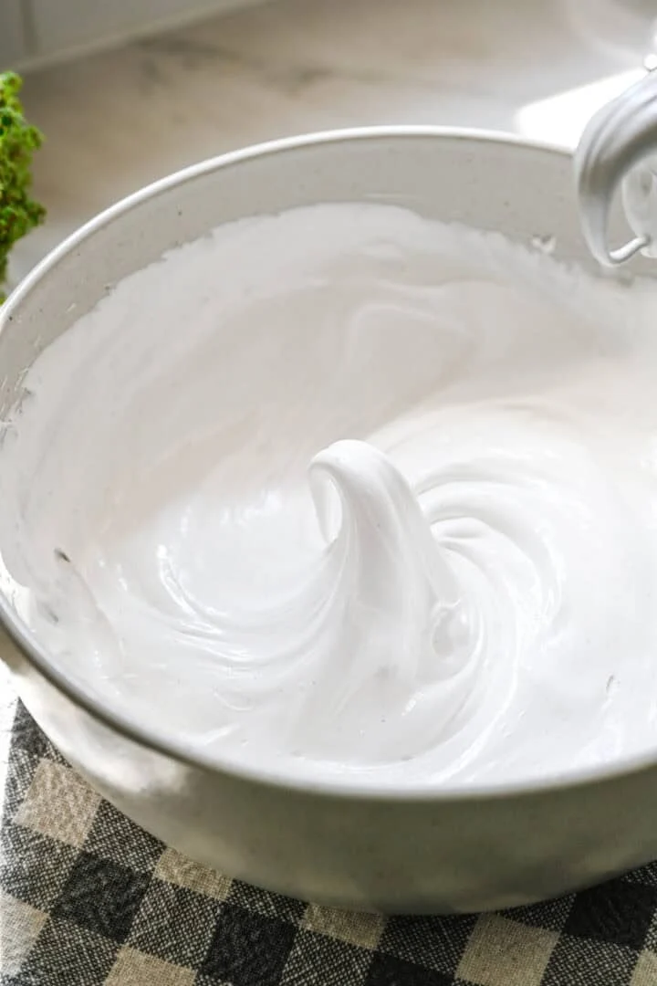 Close up view of a peak of marshmallow fluff in a white mixing bowl.