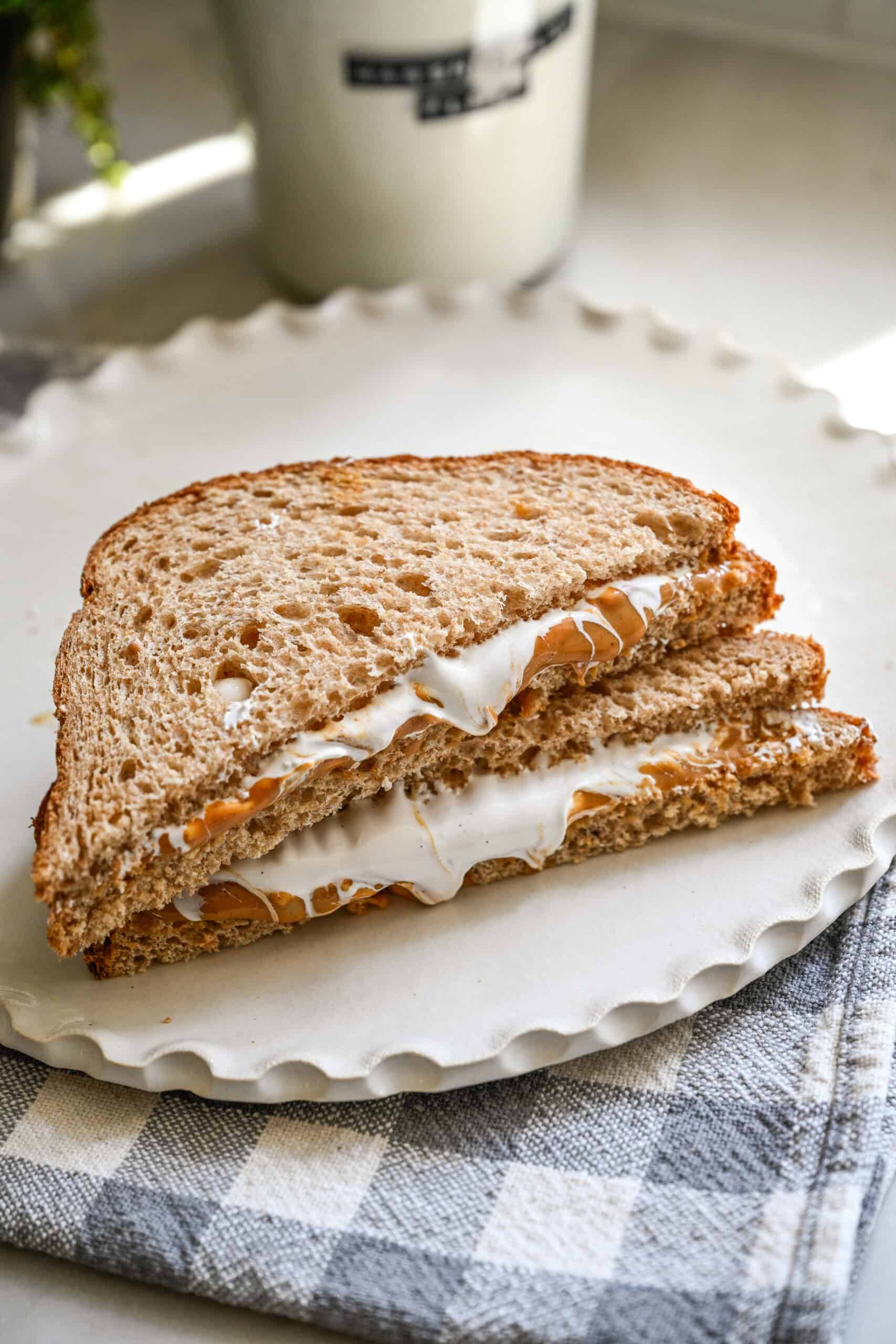 Fluffernutter sandwich with peanut butter and marshmallow fluff cut in half on a plate.