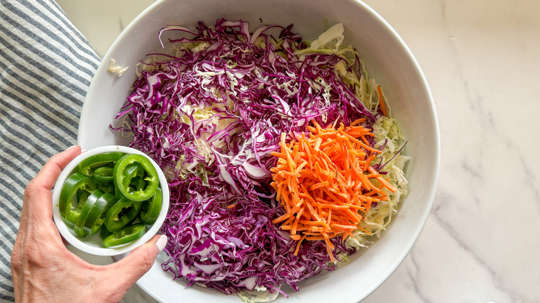 hand adding jalapeno to bowl