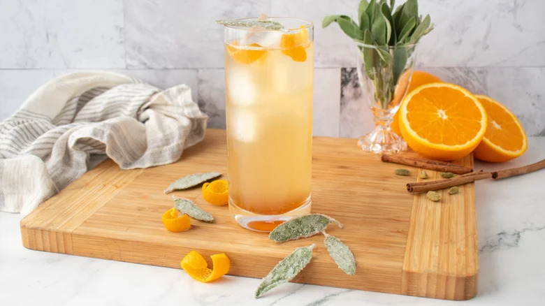 Whiskey ginger cocktail with orange and sage garnish