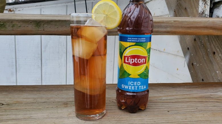 A bottle of Lipton sweet tea next to a tall glass of tea with ice and a slice of lemon