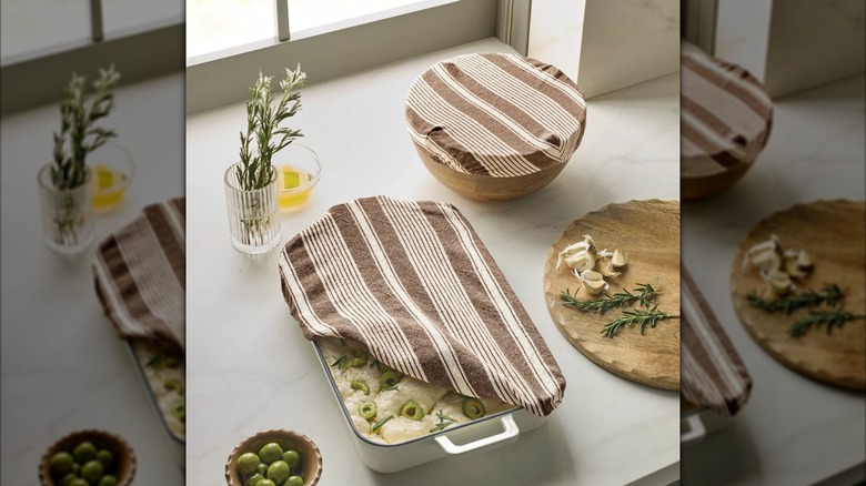 A rectangular bread bowl cover laying flat with a matching round bread bowl cover overlapping it.
