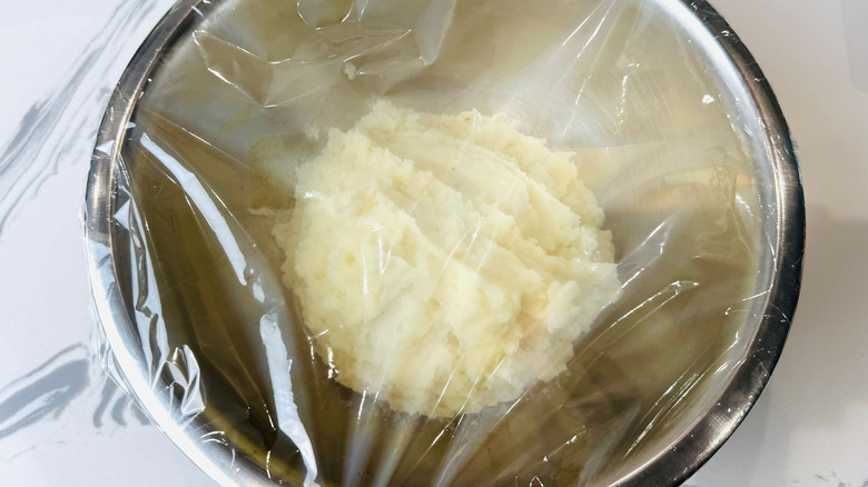 Mashed potatoes in bowl covered with plastic