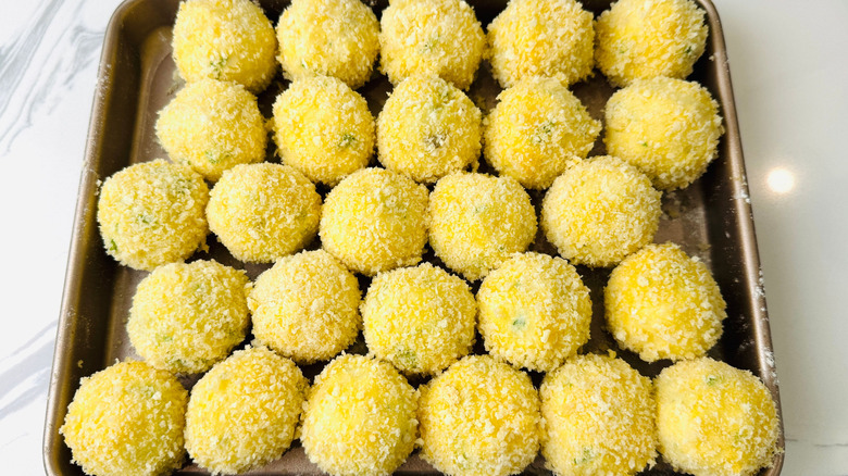 Breaded mashed potato balls on baking sheet