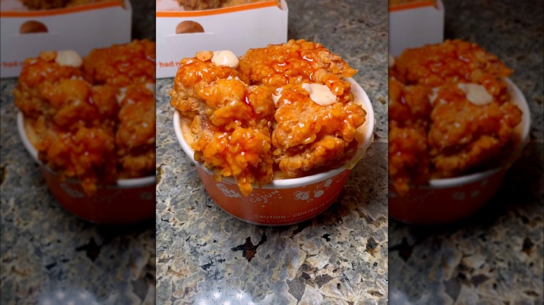 Sauced Popeyes chicken on a bowl of macaroni and cheese