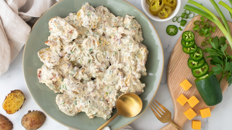 An overhead shot of a large platter with potato salad surrounded by component ingredients