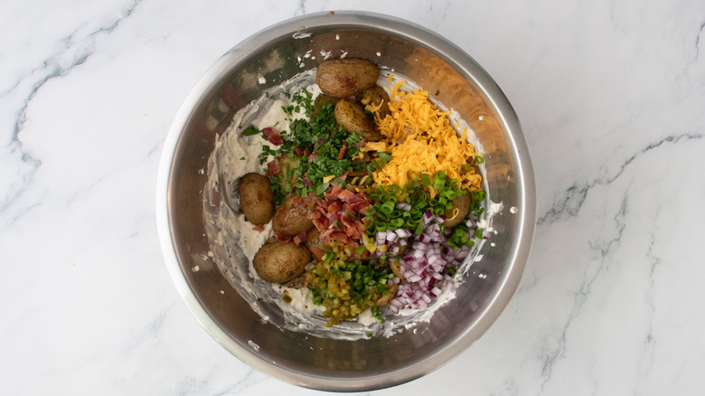 Several potato salad ingredients in a large metal bowl