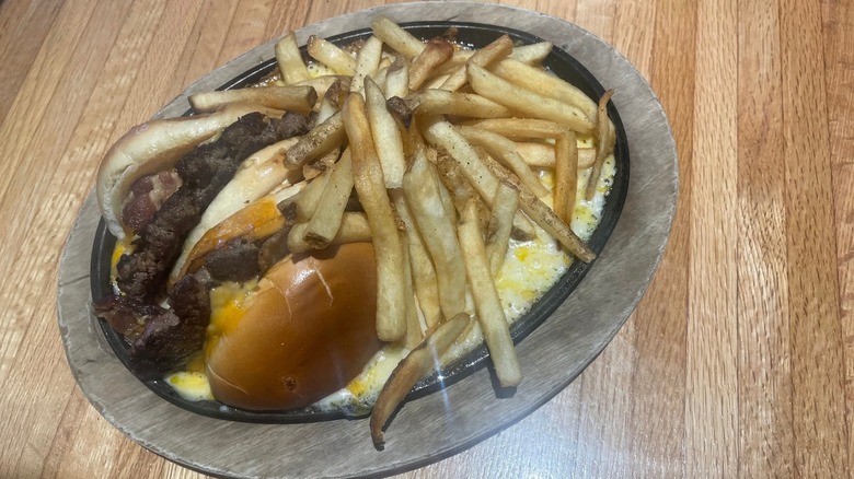 Two halves of a cheeseburger sit in melted cheese with fries.