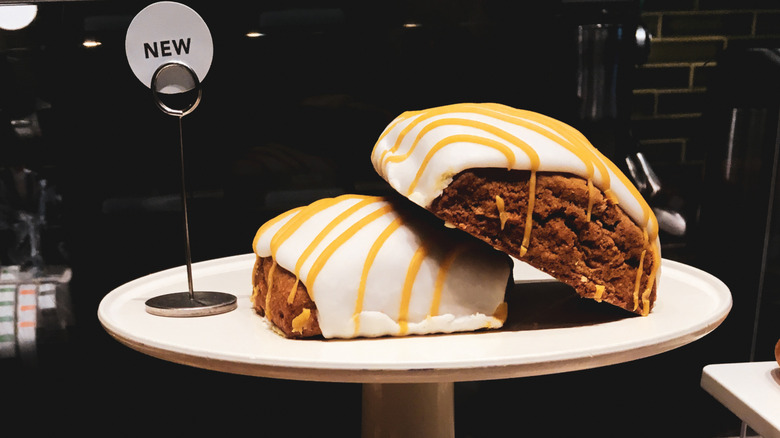 Two Starbucks pumpkin scones with white and orange icing on a pastry tray