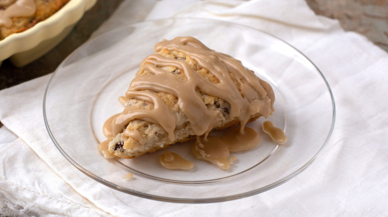 A tray of scones and one on a plate with a maple drizzle