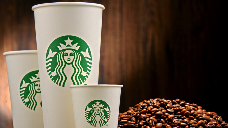 Starbucks takeout cups beside a pile of coffee beans
