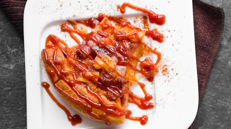 Pizza slice with toppings drizzled in ketchup