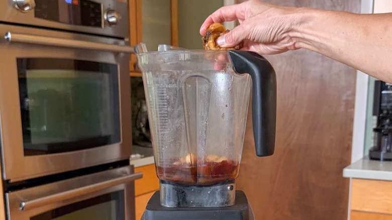 Squeezing roasted garlic cloves into blender container