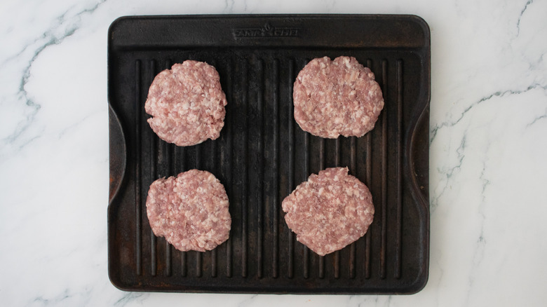 Raw pork patties on a large grill pan