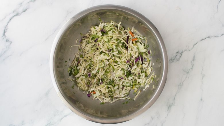 A composed coleslaw in a large metal bowl