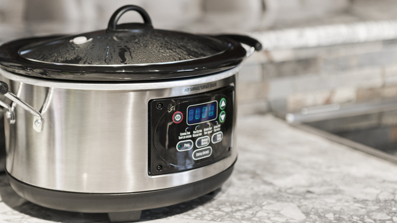 Food cooking in a stainless steel slow cooker on a marble countertop