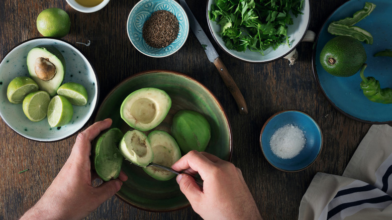 Avocados are scooped into a bowl for making guacamole