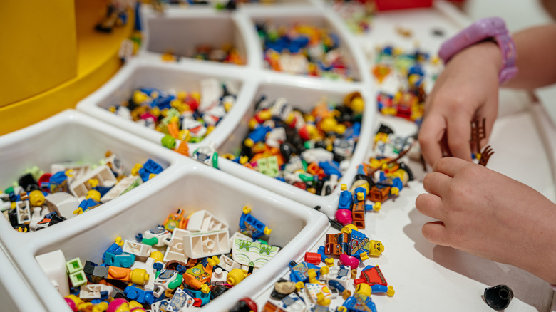 A pair of hands trying to build something from Legos.