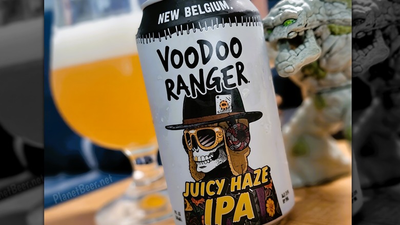 Can of Voodoo Ranger Juicy Haze IPA with glass of poured beer in the background
