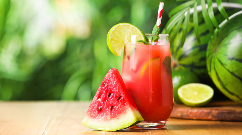 Watermelon slice next to a glass of watermelon mint lemonade