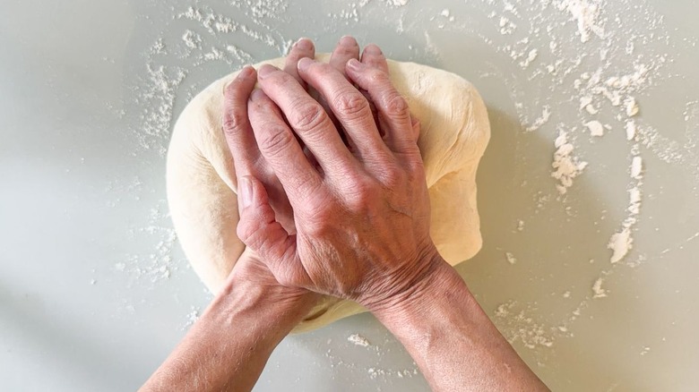 Kneading focaccia dough by hand on floured surface