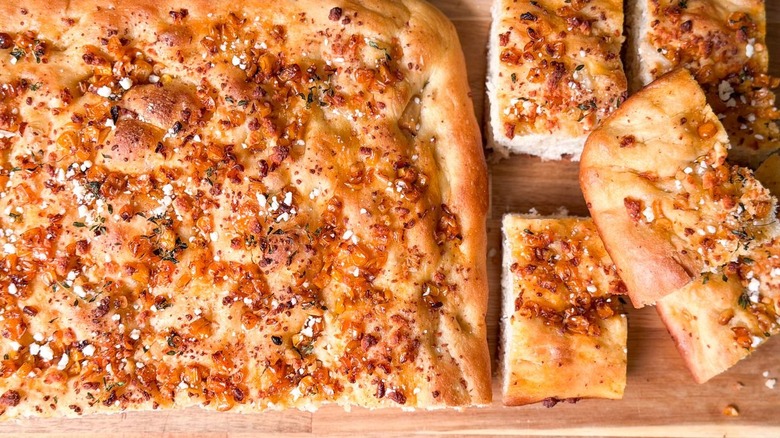 Summer corn and roasted garlic focaccia cut into squares on cutting board