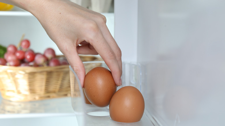 A woman taking raw eggs from the fridge.