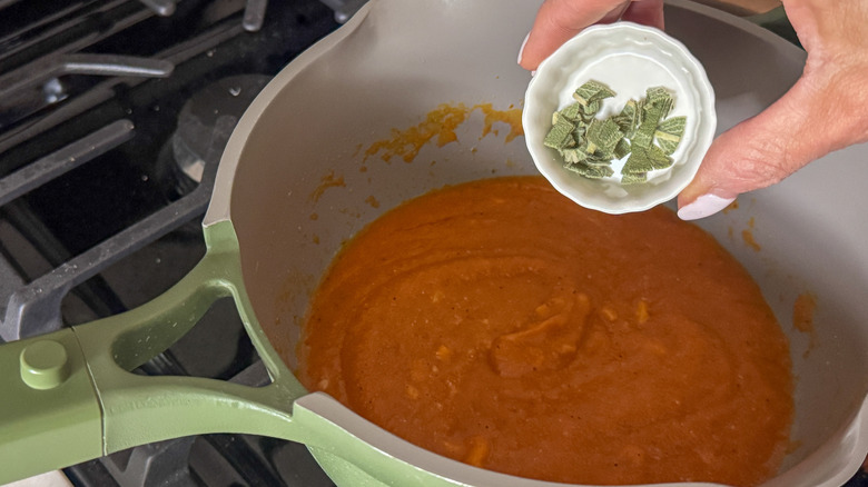 Small bowl of sage going into saucepan