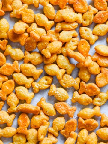 Overhead view of homemade fish shaped cheese crackers scattered on parchment.