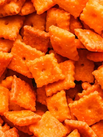 Overhead view of homemade square cheese crackers piled together.