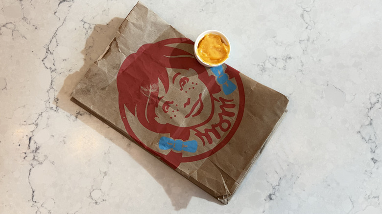A cup of Wendy's Cheddar Cheese Sauce next to a Wendy's bag