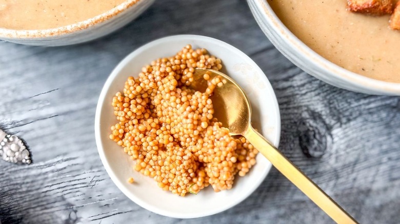 Tiny bowl filled with pickled mustard seeds and gold spoon