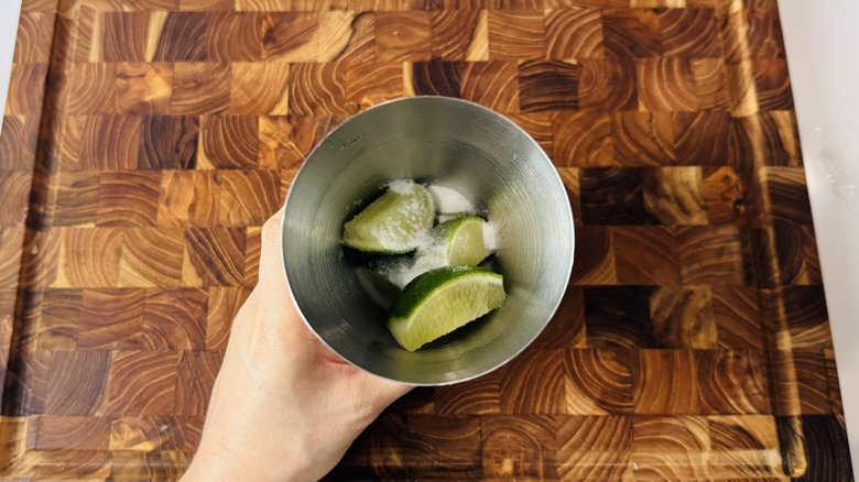 Cocktail shaker filled with limes and sugar