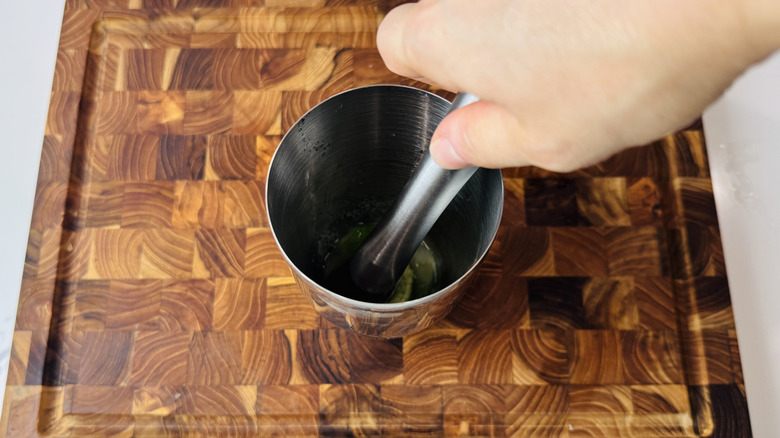 Muddling limes and sugar in a shaker