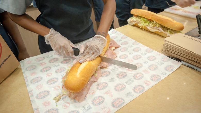An employee slices a sandwich at Jersey Mike's