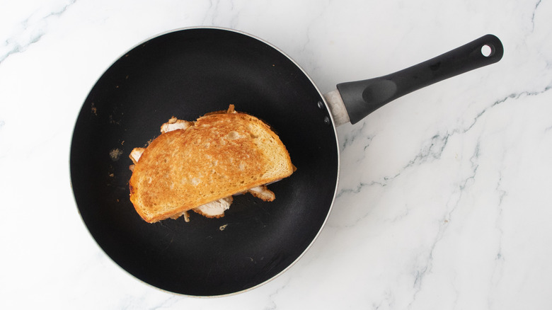 A grilled cheese sandwich in a large nonstick skillet.