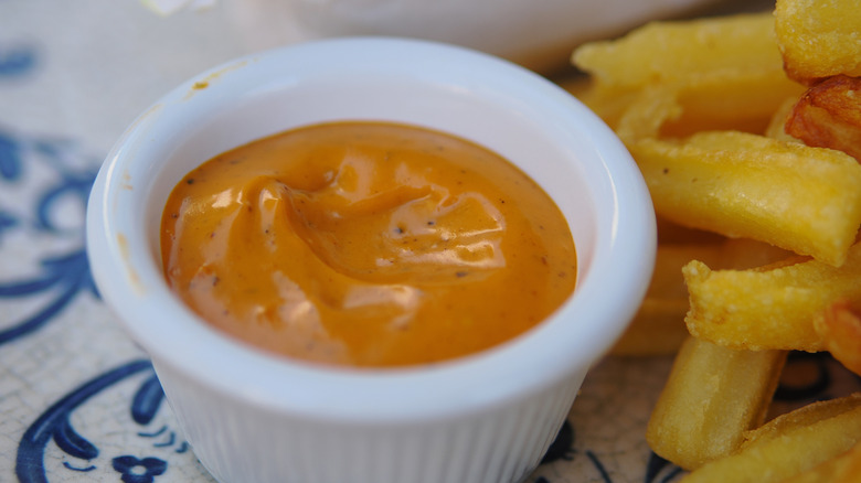 Fries with a side cup of orange sauce.