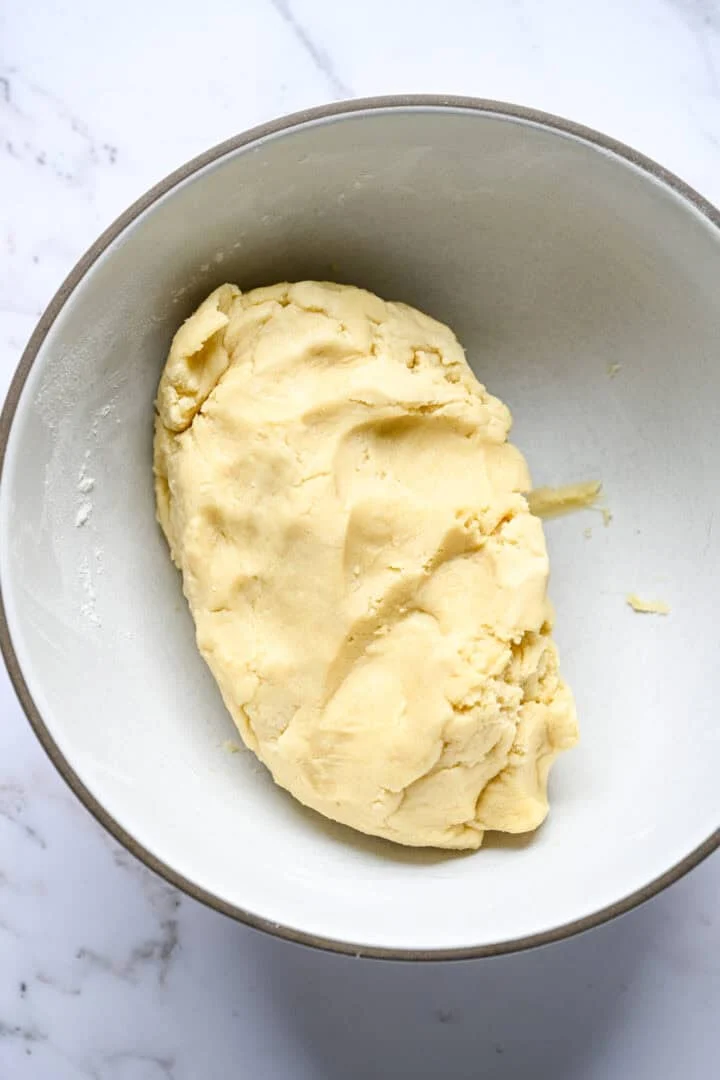 A ball of plain shortbread dough in a mixing bowl.