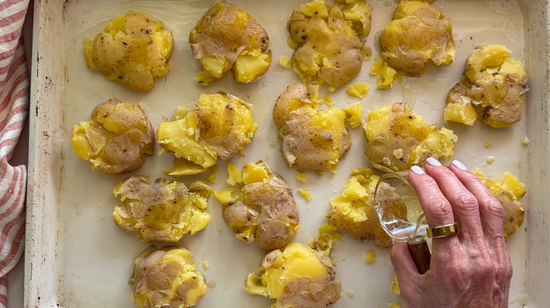 hand adding oil to potatoes